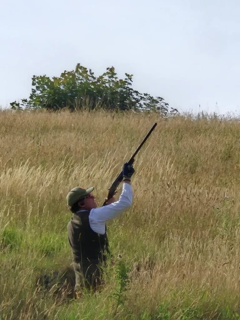 Tireur en pleine action, fusil pointé vers le ciel lors d'une battue simulée — ball trap immersif à La Planquette