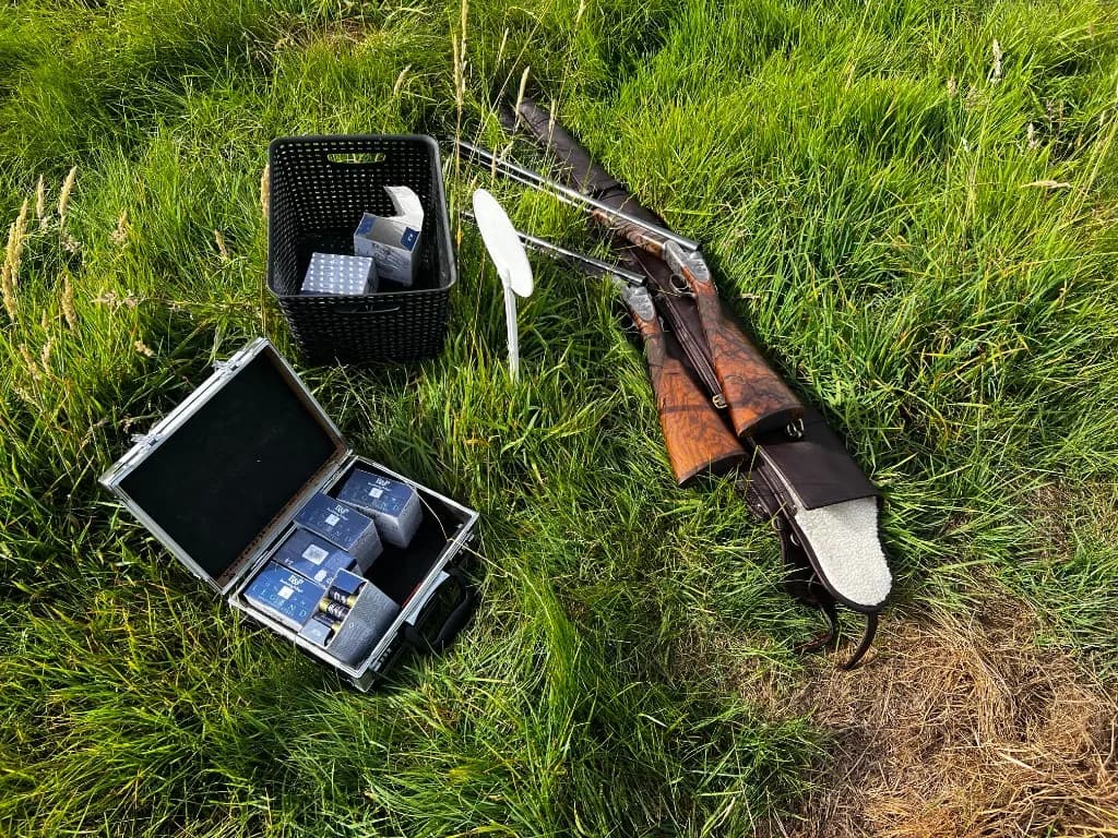 Fusil de chasse et cartouches biodégradables posés dans l'herbe lors d'une battue simulée — ball trap à La Planquette