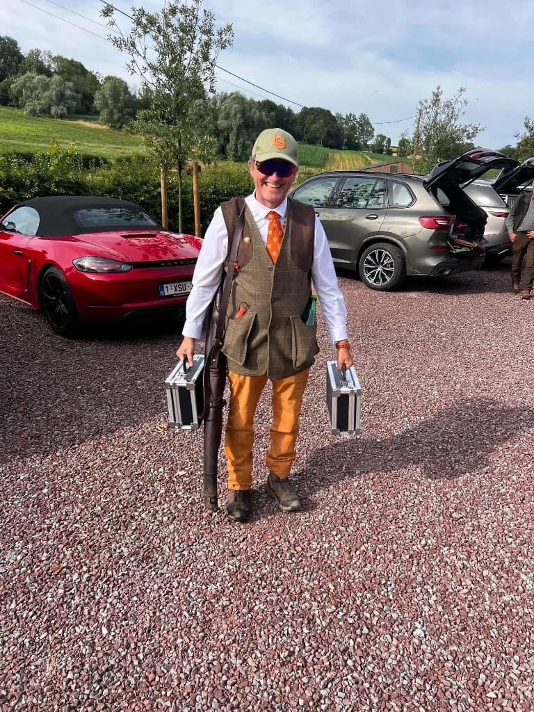 Participant en tenue de tweed portant ses mallettes de cartouches à l'arrivée de la battue simulée au Domaine de La Planquette